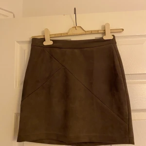 DM retro kjol  - Grå/brun/nude kjol från DM retro. Aldrig använd. Blixtlås baksidan. Väldigt skön kvalite,mocka Fraktkostnad tillkommer. 
