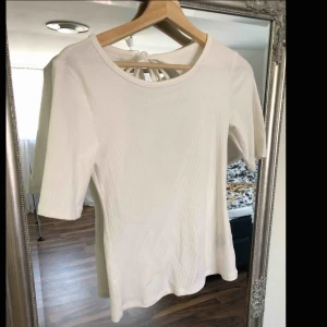  - Vit ribbad topp använd 1 gång. Öppning i ryggen.