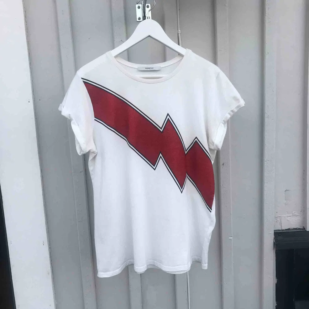 Nypris:500kr T-shirt från märket Gestuz med en röd glittrig blixt över bröstet. Använd fåtal gånger. Liten fläck, men syns knappt   Köpare står för frakt. T-shirts.