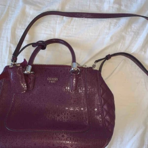  - Jätte snygg äkta Guess väska i bordeaux färg. Passar jätte bra till fest och som vardagsväska. Butikspris 1200kr. 