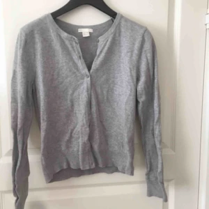  - En grå kofta med knappar fram. Köpt för ett par år sedan men nästan aldrig använd. Köparen betalar frakten