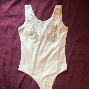  - Vit body med silvrigt tryck. Endast använd en gång och i nyskick. 