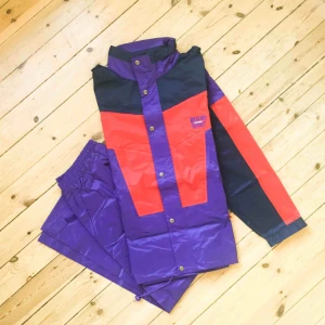  - Nytt och oanvänt set med regnjacka och byxor, unisex. Svårt att fånga färgen bra - den är inte så gäll som på bilden utan mer mörk röd och mörk lila.  Stl XXL  Har Swish. Kan skickas. Djurfritt & rökfritt hem.
