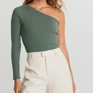 Grön ribbad one shoulder S - Väldigt fin ribbad one shoulder top med lite veckade kanter från Gina tricot i storlek S! Köpt för någon månad sen, inte kommit till så mycket användning som jag hoppades på :/ Köpt för 170kr och knappt använd alls, skriv för fler bilder🥰 