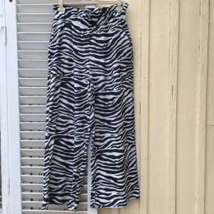 Zebramönstrade högmidjade byxor  - Ett par snygga högmidjade byxor. Utsvängda och fladdriga, plats för bälte i midjan. Använd endast två gånger, därmed i utmärkt skick. St 40-44.