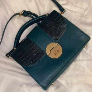 Grön snygg väska - Säljer min knappt använda gröna väska med snygga guld detaljer och snygg modell, bandet är långt och justerbart