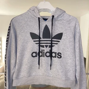 Adidas hoodie - Skriv ett pris som du skulle kunna tänka dig att ge för den. En adidashodie som slutar precis vid midjan, använd Max 3 gånger