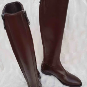  - Hög skinnstövel i klassisk design med smalt skaft.  Brun Billi Bi Copenhagen stövlar i mycket fin kvalité. Klassiskt vacker modell. Skafthöjd ca 40 cm Skaftbredd:16 x2 cm Storlek: 37 Oanvänt Helt Nya! Nytt pris runt 2799 SEK  Två dragkedja på baksidan