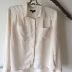  - Cremevit blus från bikbok. Stl M. Dolda knappar och två bröstfickor.  Bra använt skick.   Garderobsrensning, se mina övriga annonser. Möjlighet till samfrakt.   Köparen står för frakt. Ansvarar ej för postens ev slarv.
