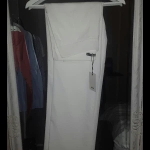  - Helt oanvända vita kostymbyxor som är hög i midjan och rak i benen, de har fickor och en dragkedja i sidan. Prislappen sitter kvar.  Har du några frågor eller vill se fler bilder så är det bara att fråga! 