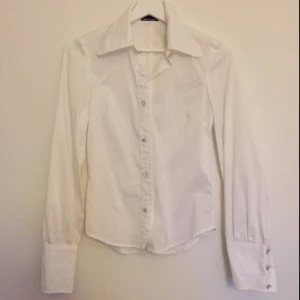  - Vit skjorta med gnistrande stendetaljer från Maria Westerlind. En knapp saknar sten. I övrigt fint skick och sparsamt använd. Passar en 34/36. Köparen betalar frakten och betalning sker via Swish.