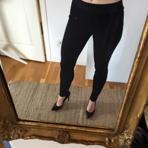  - Aldrig använda svarta byxor i "ridbyxmodell". Snygga stickningar vid sömmen på utsidan och små dragkedjor vid foten.

Märke Cambio. Bred resor i midjan.