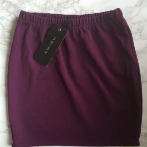  - En kort, figur sittande, mörklila kjol från Amisu i storlek 34