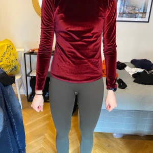 Festligare topp - En vinröd topp med tight halsring och v-öppning i ryggen. Som syns på tredje bilden så är det finns det inslag av skimmer. Kan skickas mot frakt 