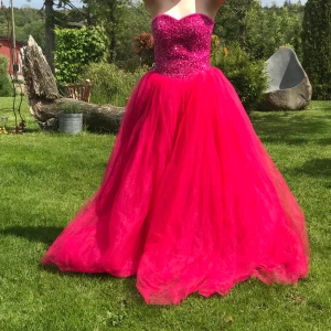 Balklänning - Rosa balklänning säljs med underkjol, köpt begagnad men inte använd pågrund tillfälle inställt. Väldigt anpassningsbar i storlek för snörning i ryggen. Frakt står köparen för. Skicka för mer info, pris går att diskutera.