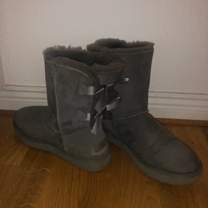 Uggs bailey - Gråa uggs med två rosetter där bak. Använda två vintrar men fint skick! Storlek 38