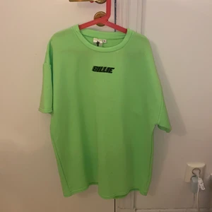 Billie Eilish merch - Snygg neongrön t-shirt från Billie Eilish egna märke köpt på hennes pop up store 2019, nästan aldrig använd därför väldigt bra skick. Lyser i blått ljus (ledlampor). Storlek XL men är inte jätteoversize, skriv gärna privat om jag ska skicka bilder på. Fraktar helst pga corona men kan annars mötas upp i Nacka! 💚
