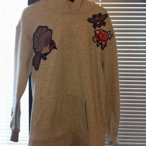 Hoodie med detaljer - Säljer denna hoodie som är i storlek M. Den är stor i storleken och även lång därför skulle den passa L/XL. Den har 4 olika detaljer på och även små slits vid sidorna. Luva har den också :)