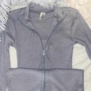 En tajt klänning ifrån nelly - En ljus grå tajt klänning med två dragkedjor man själv bestämmer hur man vill ha den. Den är i storlek XS. Skitsnygg med sneakers och man kan styla den lite hur man vill. Använd två gånger.