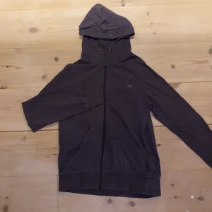 Mörkgrå zip hoddie med fickor - Assnygg lite sportig men ändå väldigt mysig mörkgrå zip hoodie utan snören, med ett litet märke, fickor och dragkedja.🤎 (Säljer pga råkade beställa dubbletter). Köpt på secondhand (från början Åhléns), men endast testad efter köpet. Ganska tunt material, ganska smal längst ner i ärmarna, och 100% bomull. (Mörkgrå, men drar lite åt både det lila och bruna hållet. Storlek XS och ni ser på bild tre hur den sitter på mig som är en XS/S. DM vid intresse/frågor/fler bilder.❣️ (Det kan du göra här under för det står ”kontakta”) Avhämtning på Södermalm eller frakt till självkostnadspris.:)