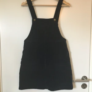 Manchesterklänning mörkblå Monki - Mörkblå manchesterklänning med hängslen från Monki. Stl. XS. Gott skick, knappt använd. Frakt betalas av köparen.