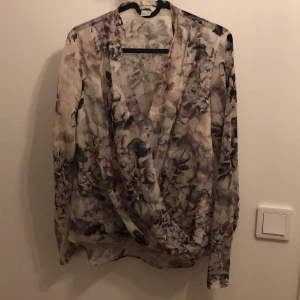 Blus - En grå/vit blus från H&M med omlott och rynk nedtill. Fin passform😍👌🏼 Lite längre baktill. 