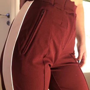 Röda kostymbyxor - Vinröda kostymbyxor med vit rand, sitter superfint!!