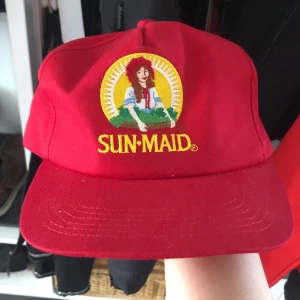 Röd sun-made keps. - Keps med loggan på russinpaketen. Köpt i USA och är i bra skick! Kan regleras där bak (Frakt tillkommer) 