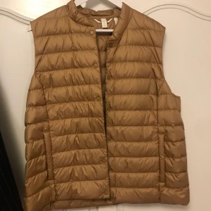 Tunn väst  - En tunn väst utan luva från H&M. Västen är i en mörk nyans av beige. Aldrig använd. mycket bra skick