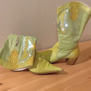 Cowboy boots - Pastell grön-gula boots i ormskinsimitation och fet fjäril på framsidan. I mörka miljöer lyser silvret när det reflekteras i ljus;) 🦋 Frakt tillkommer men vet ej vad den ligger på än<3 högsta bud 400. Köpta på Callameinte Jane’s 