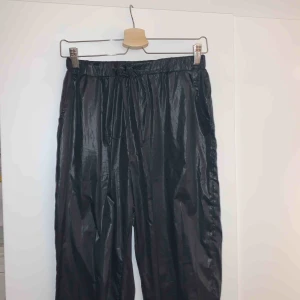  - I princip nya svarta, blanka, tunna prasselbyxor från Missguided, endast prövade och tvättade 1 gång.  Säljer pga aningen för små, tror dom sitter snyggast på en 38-40a i byxor!  + dragsko i den höga midjan och små fickor i sidorna. 