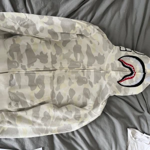 Zip hoodie - L små i storlekar,8/10 skick, zip hoodie från amazon  Unik vit Bape zip hoodie! Stilfull streetwear för dig.  Kontakta mig om du undrar över något. LIKNADE