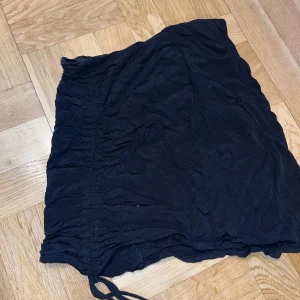 Kjol - Svart kjol med scrunch på sidan väldigt skrynklig då den legat i min byrålåda under hela vinter och har ej stryckjän tillgänglig men går att fixa efter en strykning