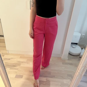 Rosa satinbyxor - Rosa satinbyxor från Nelly. Storlek 34. Aldrig använda, men uppsydda med 2 stygn på vardera ben för att passa mig som är 167 cm lång. Går lätt att ta bort.