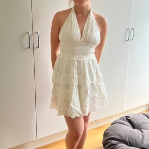 Miniklänning med halterneck  - Klänning köpt från Asos av märket Miss Selfridge som för tillfället är slutsåld. Elfenbensvit miniklänning med smockad midja och halterneck i broderie anglaise. Oanvänd med lappar kvar. 