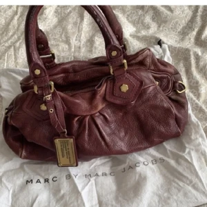 Marc Jacobs väska - Säljer vintage marc Jacobs väska i mörkare vinröd nypris 5500kr,obs bilderna är lånade!skicket är använt haren del repor,man får avgöra själv på bilderna jag kan skicka❣️lite missfärgningar oxå på vissa ställen,täcken på användning!Inget paxas,tryck på köp