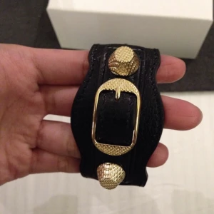 Balenciaga armband  - Säljer mitt coola balenciaga armband med guld nitar! Tyvärr har det slitits en del vid spennet, därav det låga priset, men det är inget som syns när armbandet väl är på! Skriv till mig för fler bilder❤️☺️