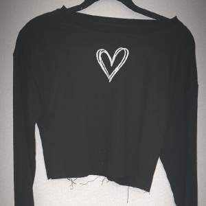 En svart långärmad tröja med ett vitt hjärta i mitten 