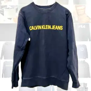 En collegetröja från Calvin Klein. Marin med gul text. I använt skick men fin. 