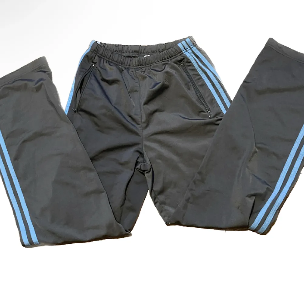 Adidas byxor av ”sportigt” material, kan vikas ned och bli lågmidjade . Inga Defekter, mörkgråa med ljusblå ränder. Jeans & Byxor.
