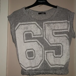 Kort topp/linne - Melerad grå  kort topp/ t shirt  med gummitryck~ scabby look, rullarm och dolt bred resår i midjan, mjuk o skön. 