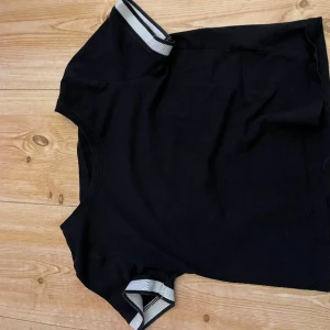 T-shirts från h&m - En svart T-shirt från H&m med vita ränder i strl 146/152 i bra skick säljer för 10kr