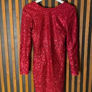En röd paljettklänning men en djup urringning i ryggen, klänningen är i mycket bra skick! (Den ligger ut på fler sidor, så köper någon den innan så går jag på det)