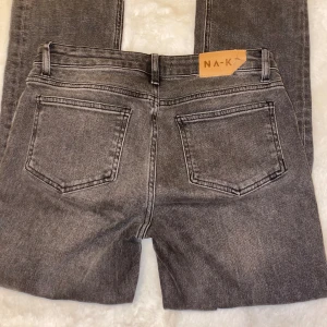 Lågmidjade jeans - Gråa lågmidjade jeans från nakd. Raka i modellen med en slit längst ner. Jättefina men tyvärr blivit förstora.