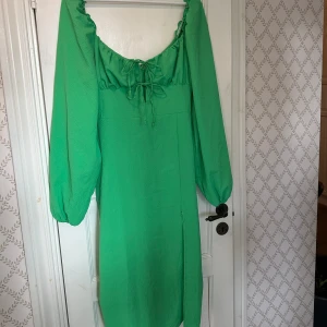 Klänning  - Klargrön midiklänning med slits och söta rosetter vid bysten. Storlek 38, aldrig använd.