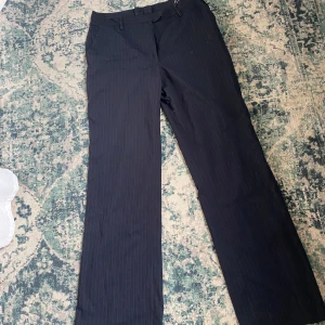 Marinblå kostymbyxor - Vintage mid/low waisted, randiga, kostymbyxor. Storlek 40 men det har sytts in i midjan(se bild 2). Skulle säga att de är 36/38 i stl. 