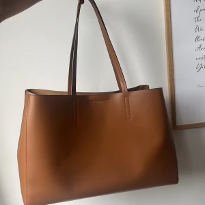 Toteväska - En super elegant och rymlig toteväska från märket ”Wera” i färgen Congac (material:skinn). Perfekt till skola, jobb eller till vardags ✨Den kan även formas på två olika sätt. Ord pris: 1499 kr  Bredd: 42 cm Höjd: 23 cm Djup: 13 cm 
