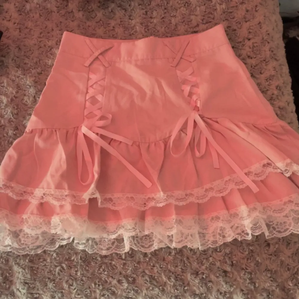 Jättefin rosa kjol med vit lace och rosetter! Passar jätte bra för höst, sommar eller vår garderob.  Är bara använd några gånger hemma och har inga fläckar/ skador.. Kjolar.