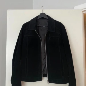 Rock and blue mocka jacka  - Snygg svart jacka med dragkedja framtill och fickor på sidorna. Jackan har en klassisk design och är perfekt för både vardag och fest.