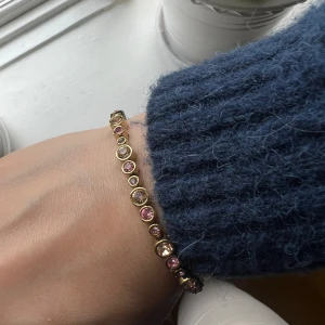 Dyrberg/Kern armband - TERESIA - ett av DYRBERG/KERNS mest populära armband. Feminint och tidlöst med vackra persikofärgade kristaller i olika storlekar. Smycket är tillverkat i polerad mässing med en guldtonad IP plätering.  Längd 17 cm + förlängningskedja.  Handgjort och